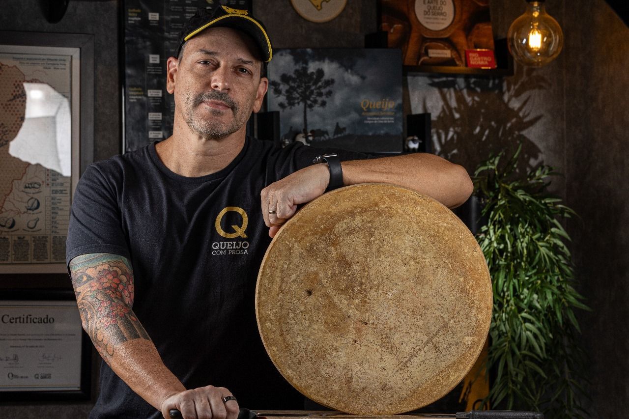 Um homem está segurando um grande pedaço de queijo nas mãos.