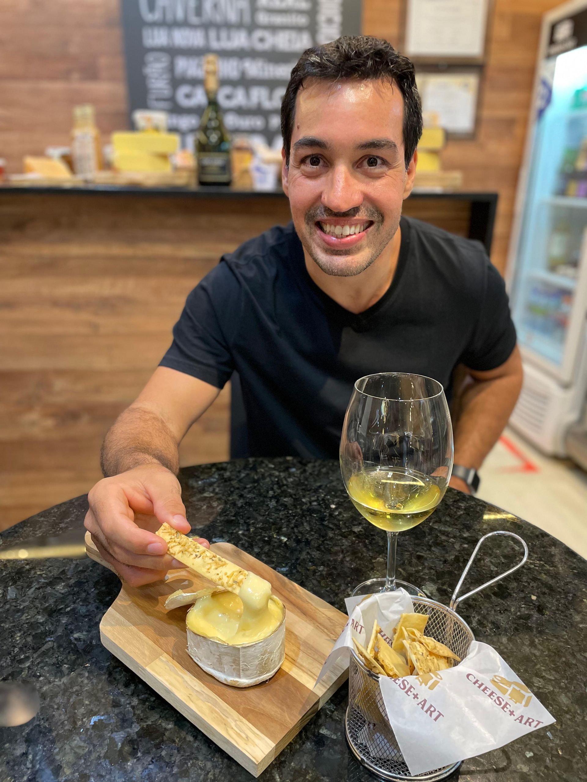 Um homem está sentado à mesa com um prato de comida e uma taça de vinho.