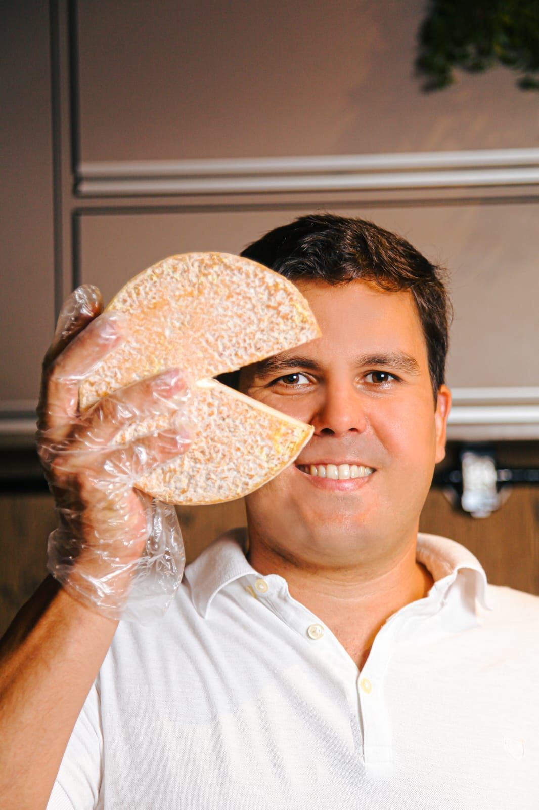 Um homem está segurando um pedaço de pão na frente do rosto.