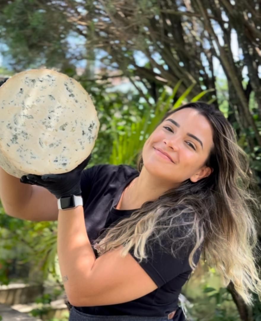 Uma mulher está segurando um grande pedaço de queijo nas mãos.