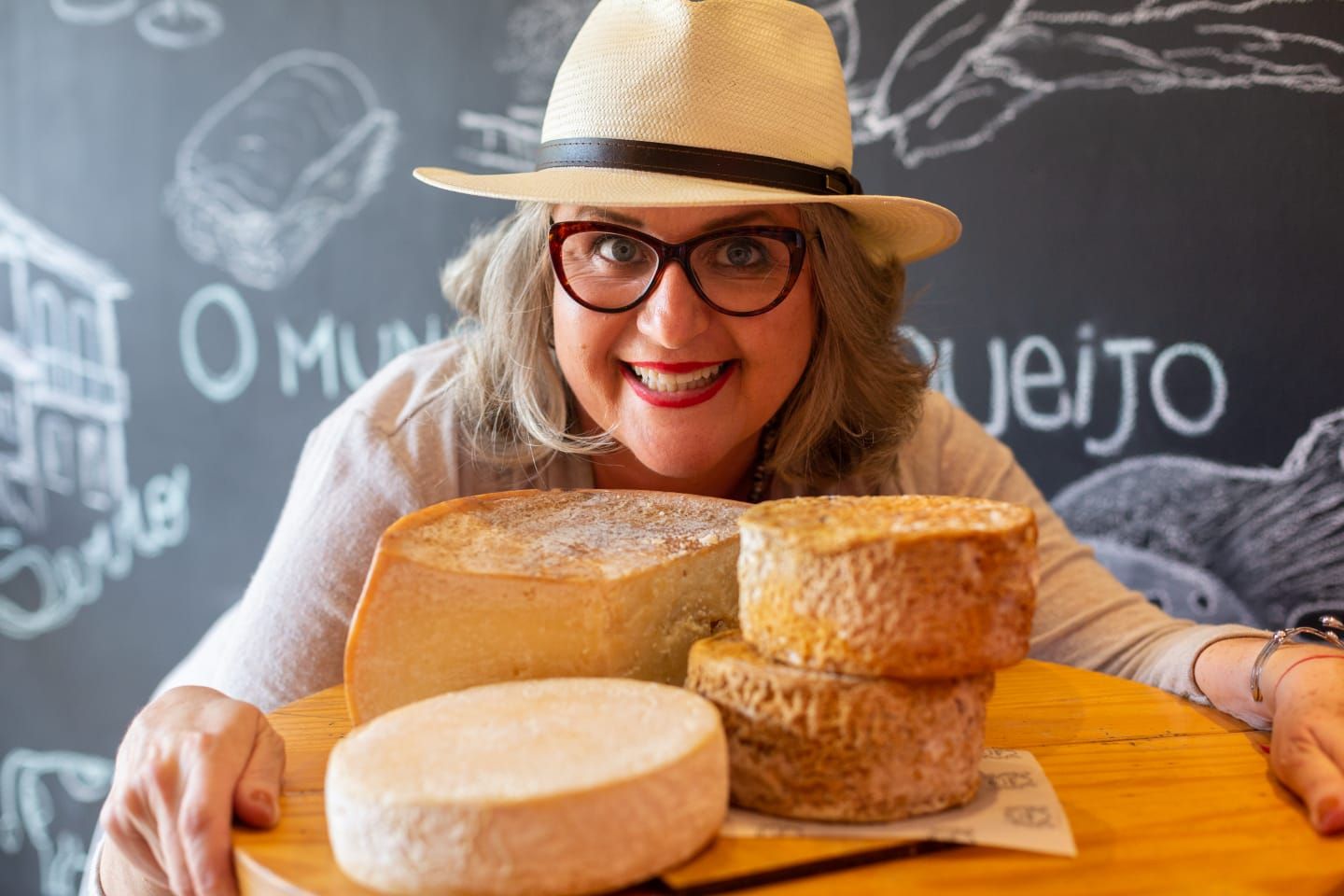 Uma mulher usando chapéu e óculos está segurando uma bandeja de queijo.