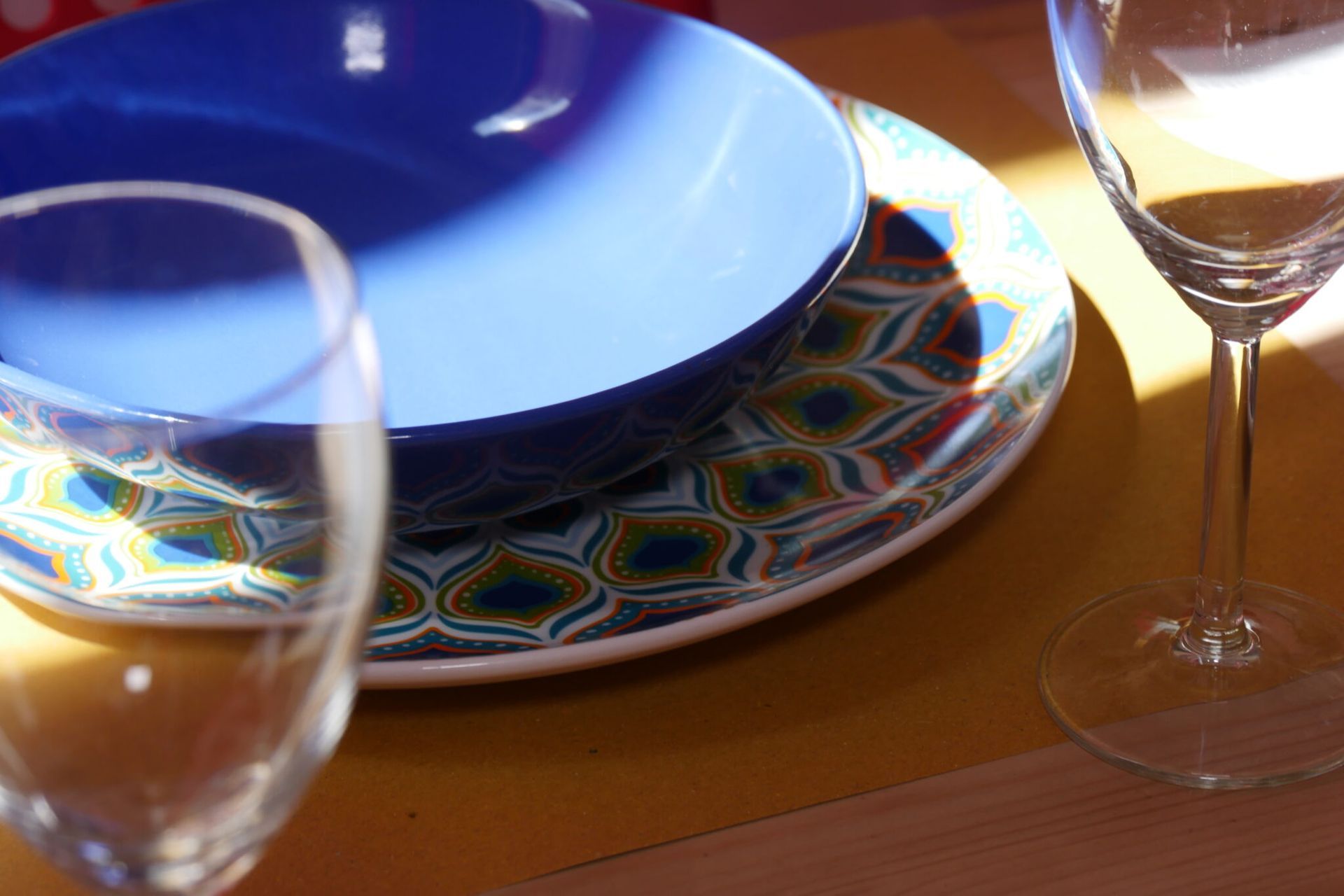 un tavolo con un piatto blu e due bicchieri di vino