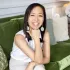 A woman is sitting on a green couch and smiling.