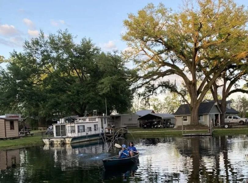 Small boat on a calm lake with houses and trees reflecting in the water at dusk