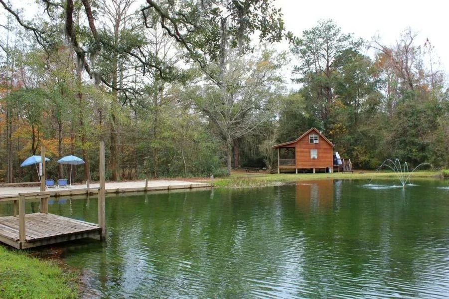 Peaceful lake with a small dock, trees, and a red cabin on the shore