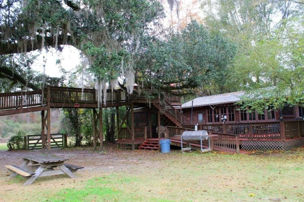Rustic outdoor picnic area with wooden decks, tables, and trees in a grassy yard