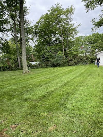 A man is mowing a lush green lawn in front of a house.