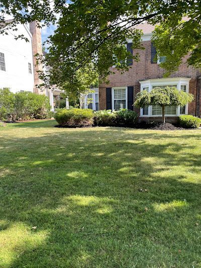 A large lush green lawn in front of a brick house.