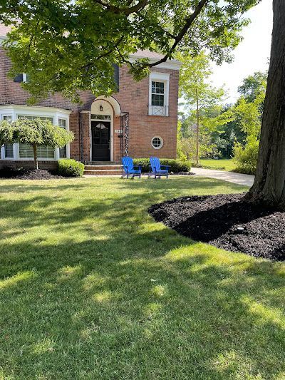 A brick house with a large lawn in front of it.
