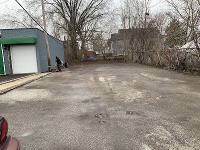 An empty parking lot next to a building with a green door.