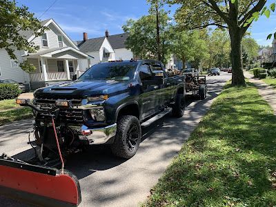 A black truck with a snow plow attached to the front is parked on the side of the road.