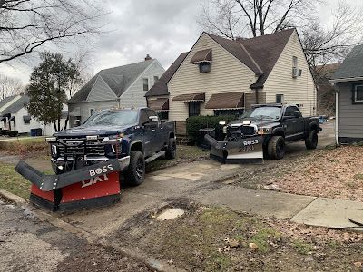 Two snow plows are parked in front of a house.