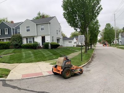 A lawn mower is parked on the side of the road in front of a house.