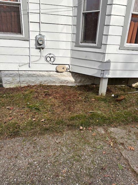 Exterior of a white house with grey trim and a patch of dry grass in front.
