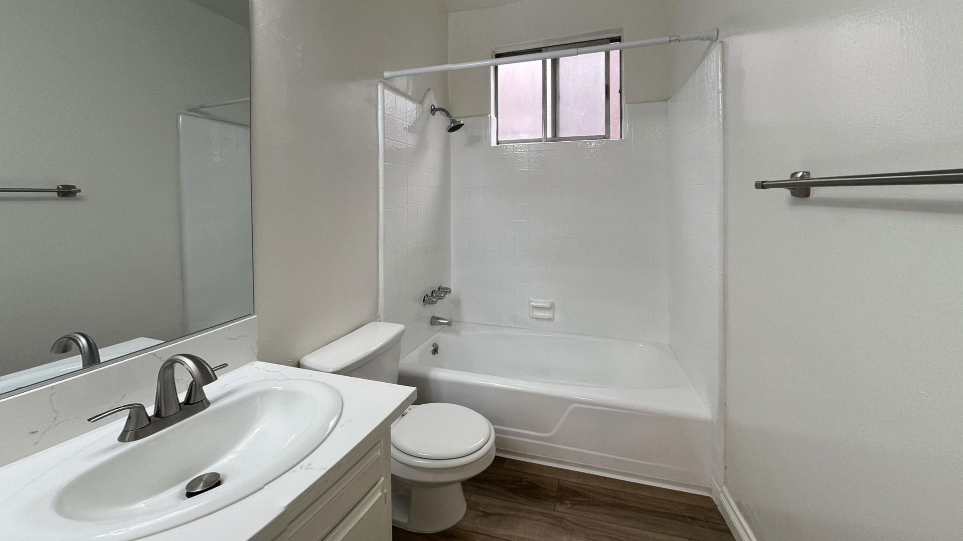 Bathroom with white walls, a vanity, toilet, and a bathtub with a shower curtain.