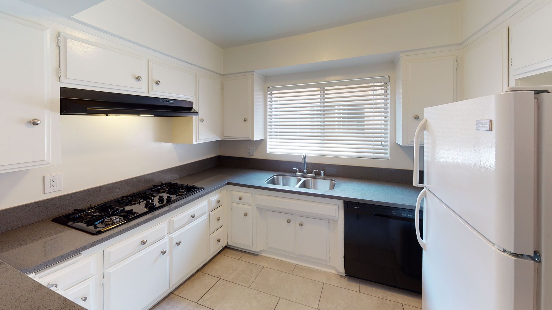White kitchen with gray countertops, gas stovetop, and white appliances.