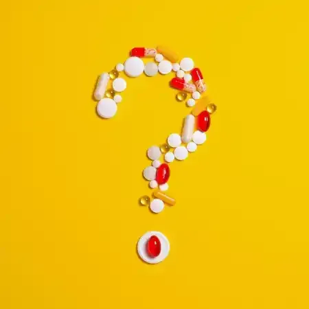 Question mark symbol made of pills on a yellow background.
