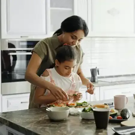 Woman and child cooking together in a kitchen, preparing food on a countertop.