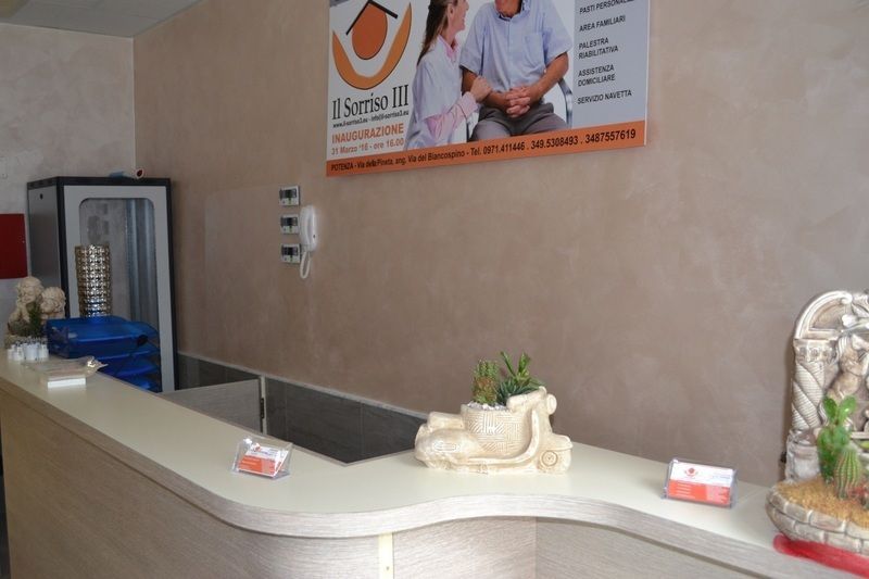 Banco della reception di una clinica, con un distributore d'acqua, un'insegna e piante decorative.