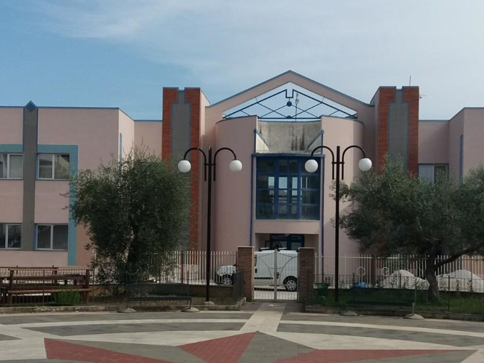Edificio rosa chiaro con dettagli blu, ingresso ad arco e lampioni.