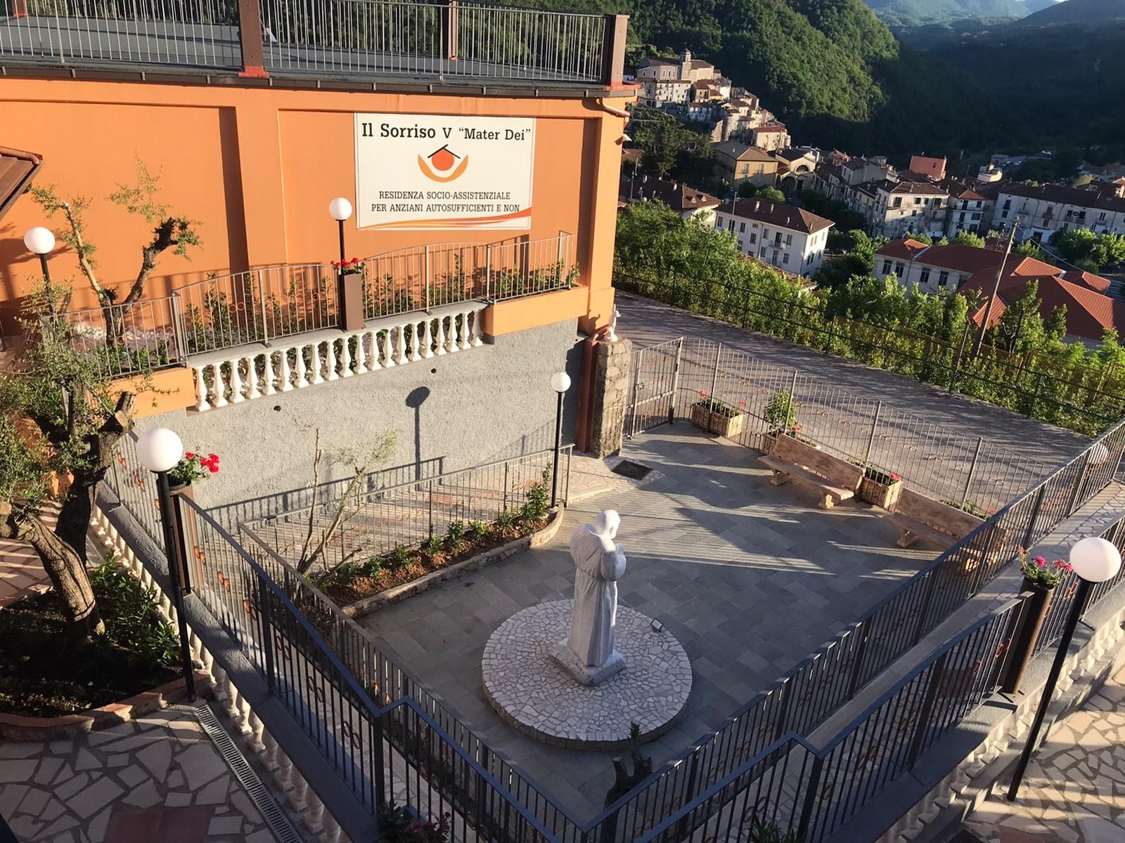 Cortile con statua, edificio e vista panoramica sul villaggio.