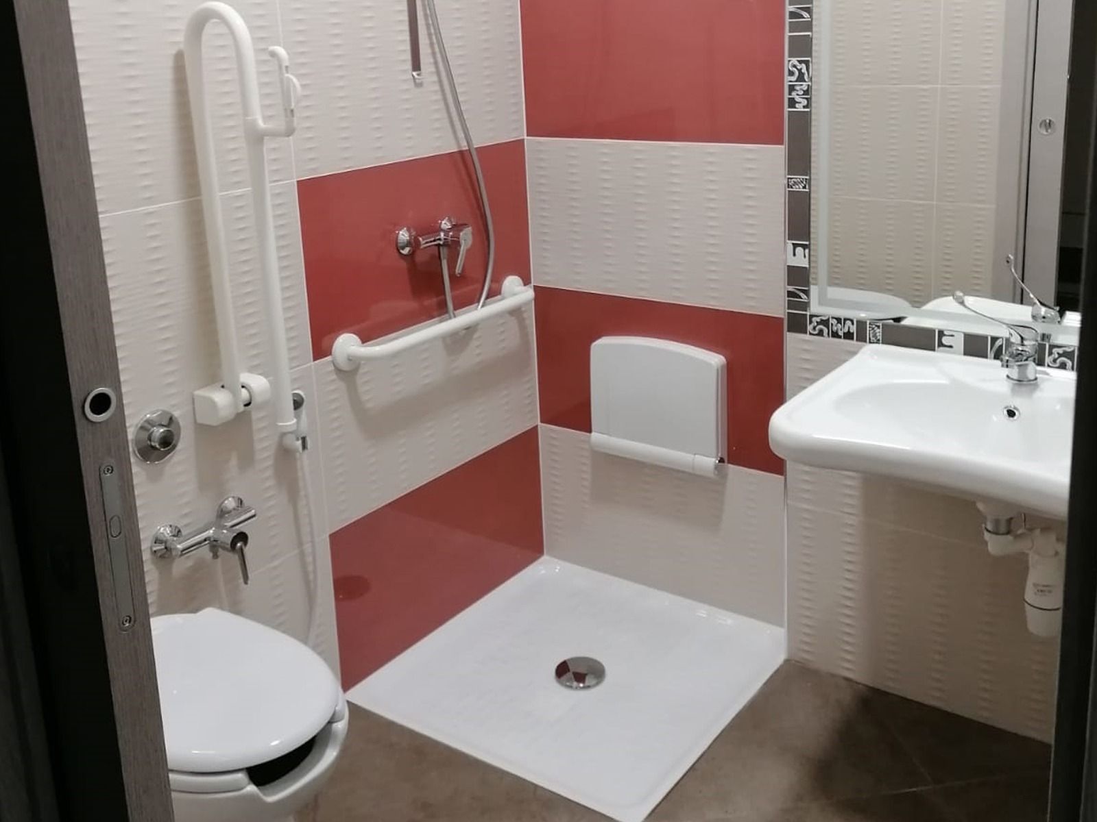 Bagno accessibile con doccia, WC e lavandino accessibili. Include maniglioni e sedile per doccia ribaltabile.