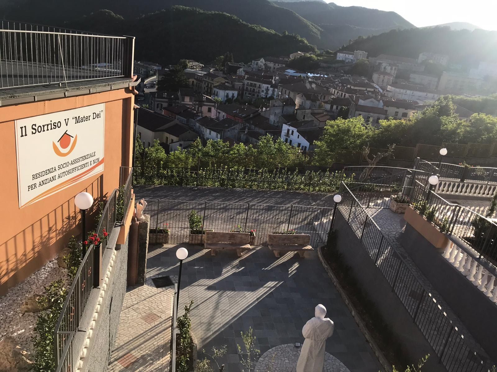 Vista di una cittadina collinare da una terrazza, con l'insegna di un ristorante e una statua.