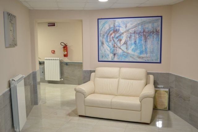 Corridoio con divano color crema, opere d'arte astratte, pareti beige e un estintore.