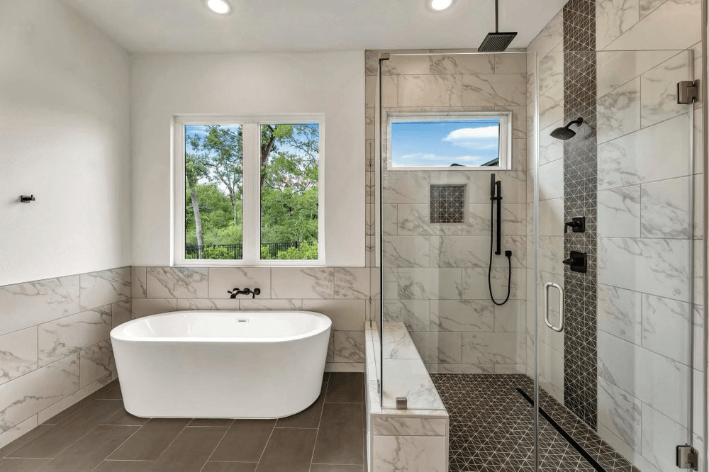 Bathroom with a white tub, shower with patterned tile and a pebble floor.
