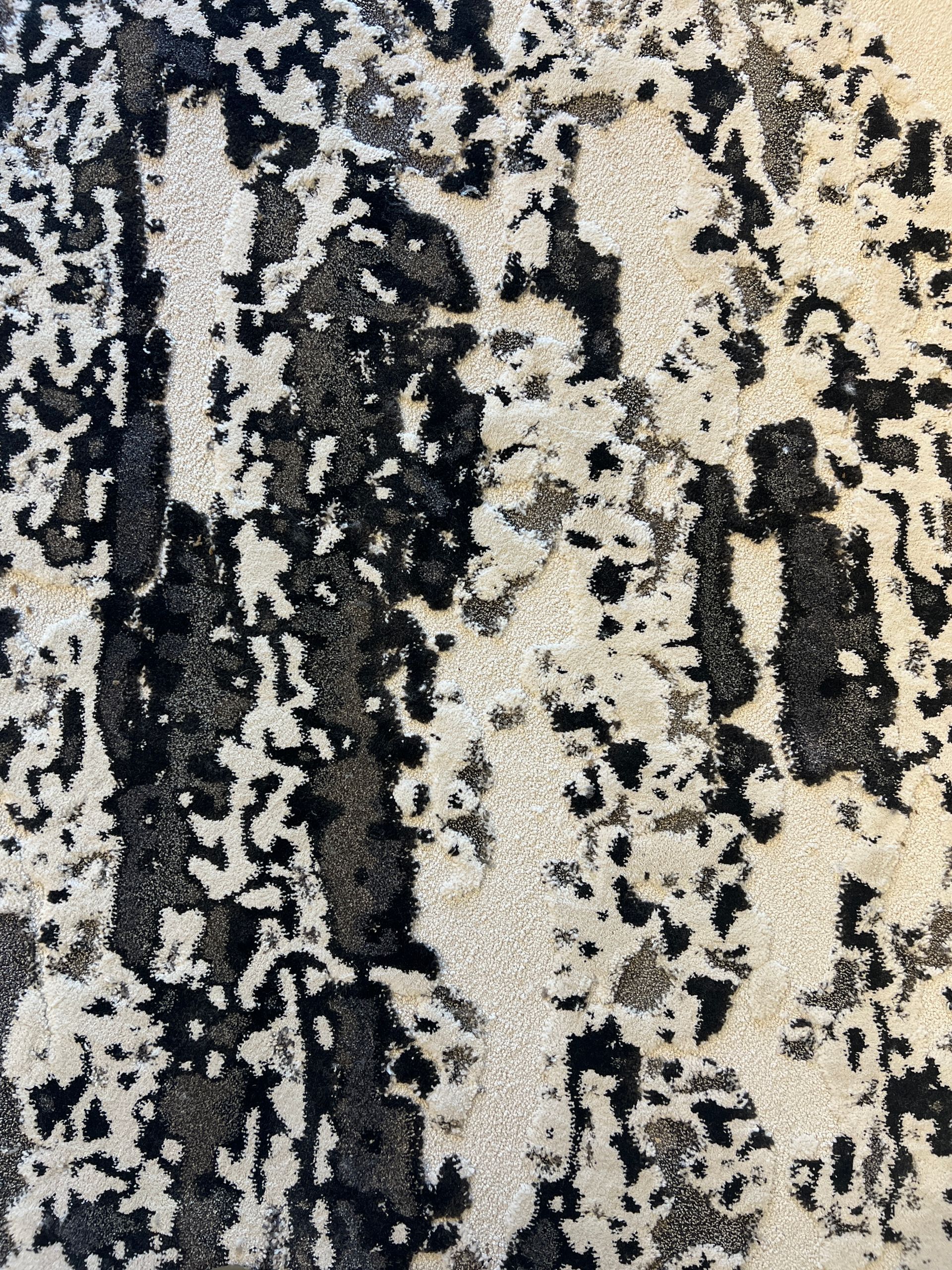 Abstract rug with black and beige patterns.