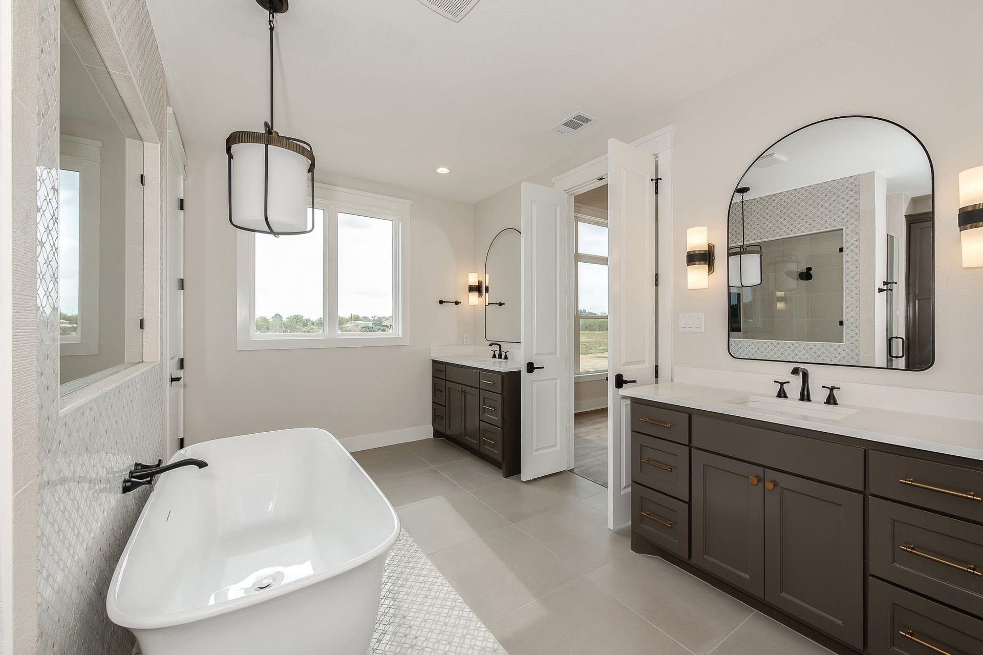 Modern bathroom with patterned tile walls, freestanding tub, and pebble shower floor.
