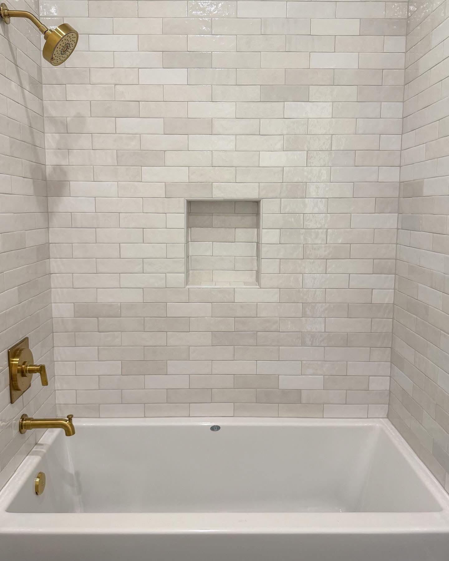 Modern bathroom with patterned tile walls, freestanding tub, and pebble shower floor.