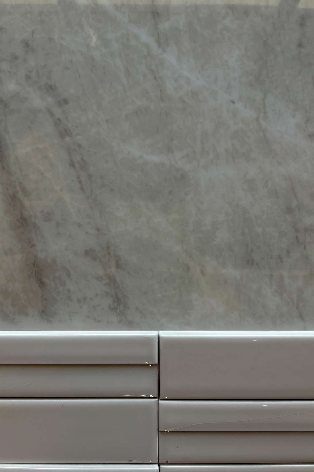 Gray and white tile with marble-patterned wall.