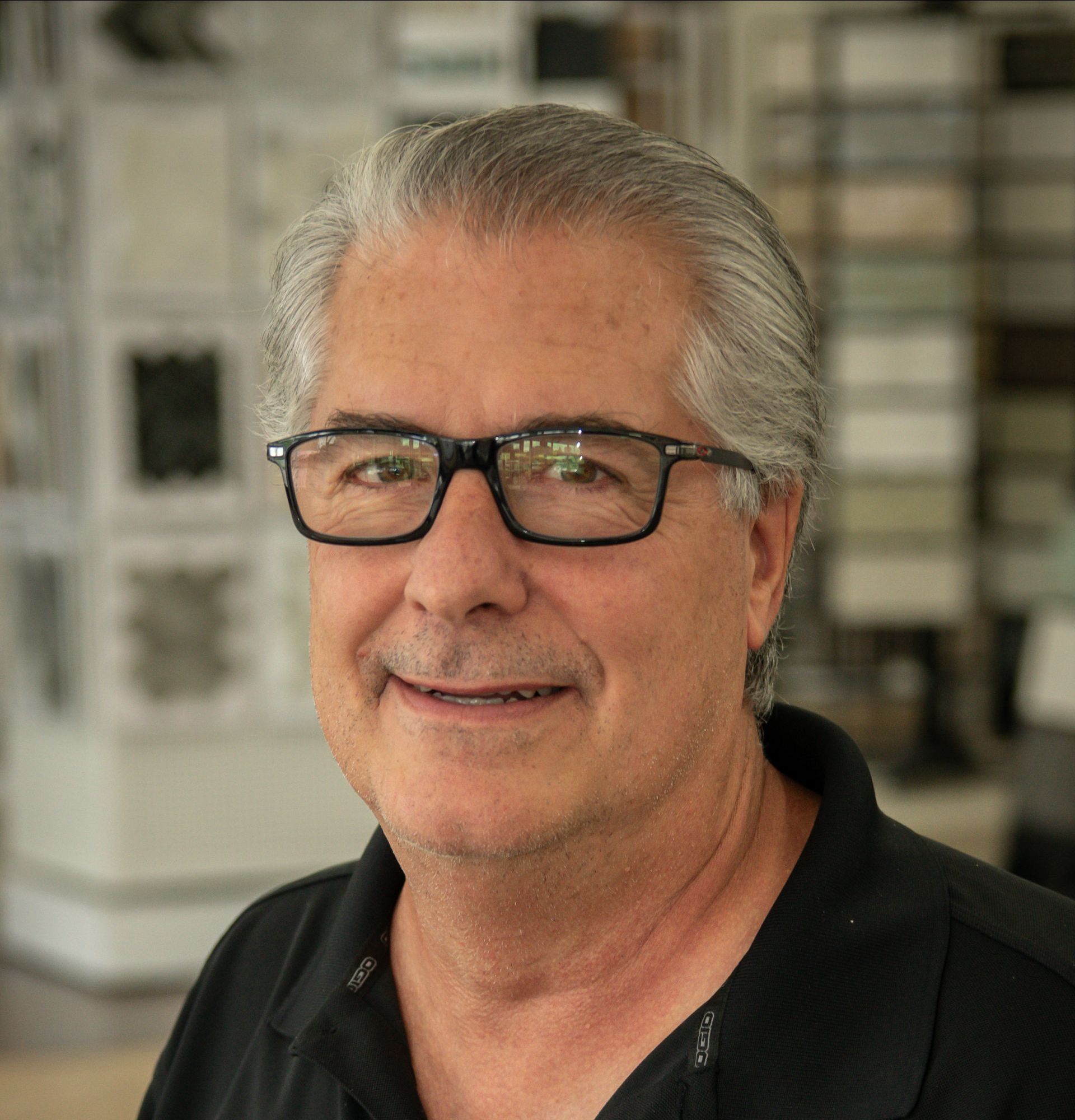 A man wearing glasses and a black shirt is smiling for the camera.
