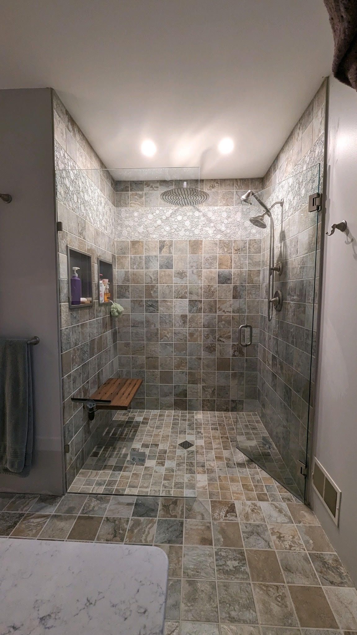 A bathroom with a walk in shower and a bench.