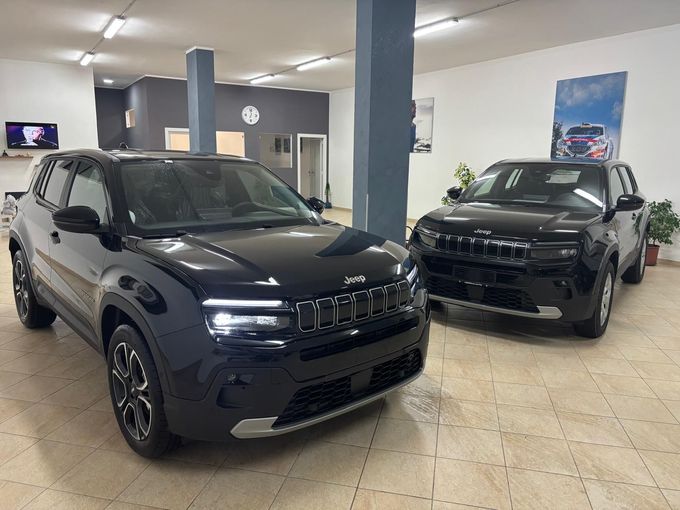 Vista frontale sinistra di un SUV blu scuro con faro circolare illuminato e dettagli della griglia all'interno