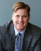 A man in a suit and tie is smiling for the camera.