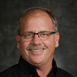 A man with glasses and a mustache is smiling for the camera.