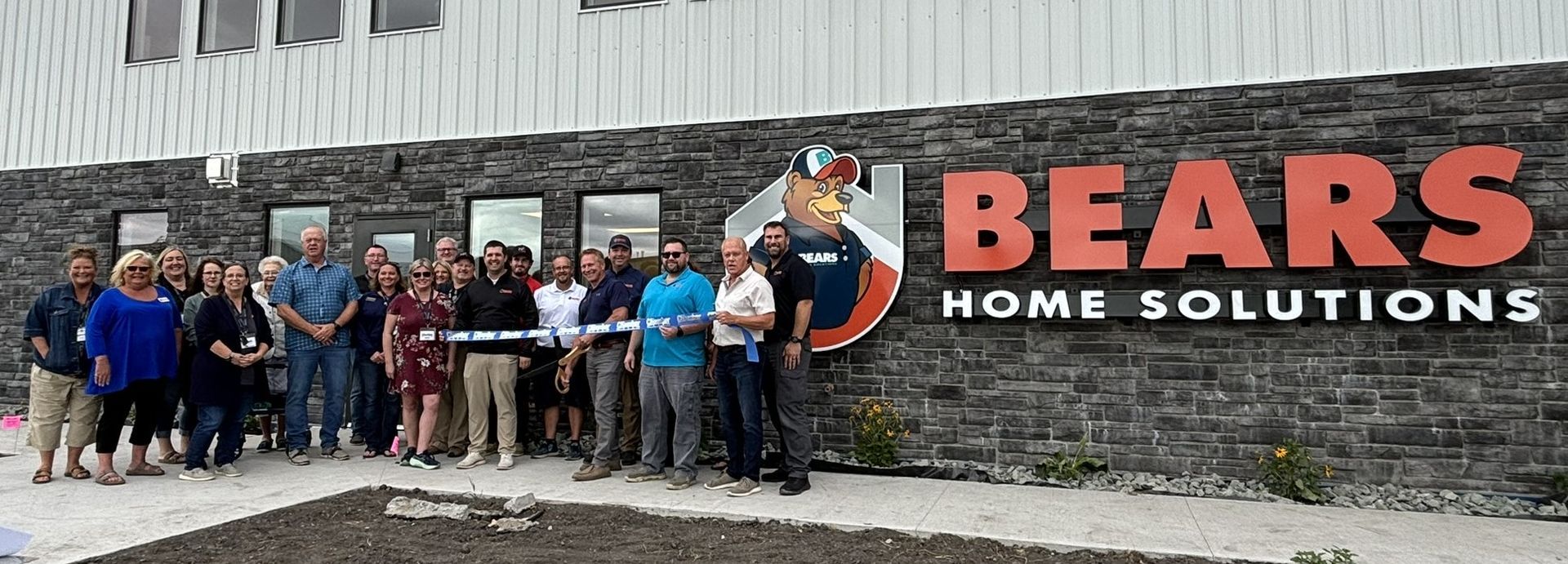 A group of people are standing in front of a bears home solutions sign.
