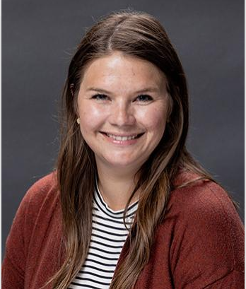 A bald man in a suit and blue shirt is smiling for the camera.