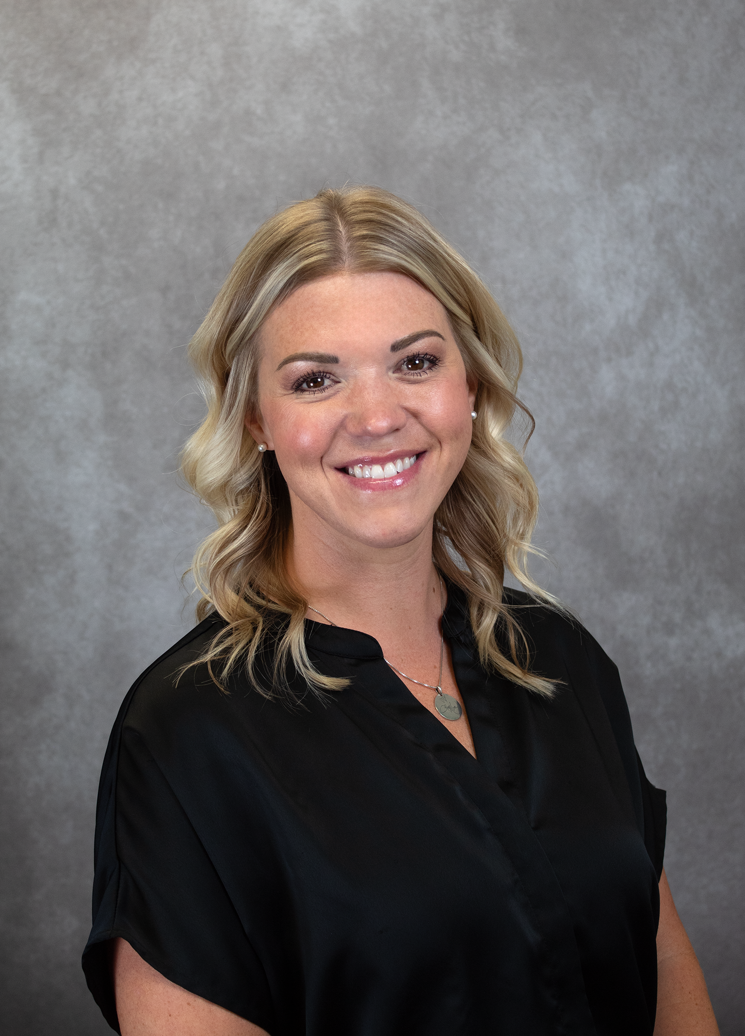 A woman wearing glasses and a striped jacket is smiling for the camera.