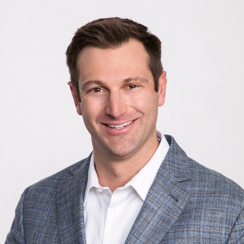A man in a suit and tie is smiling for the camera.