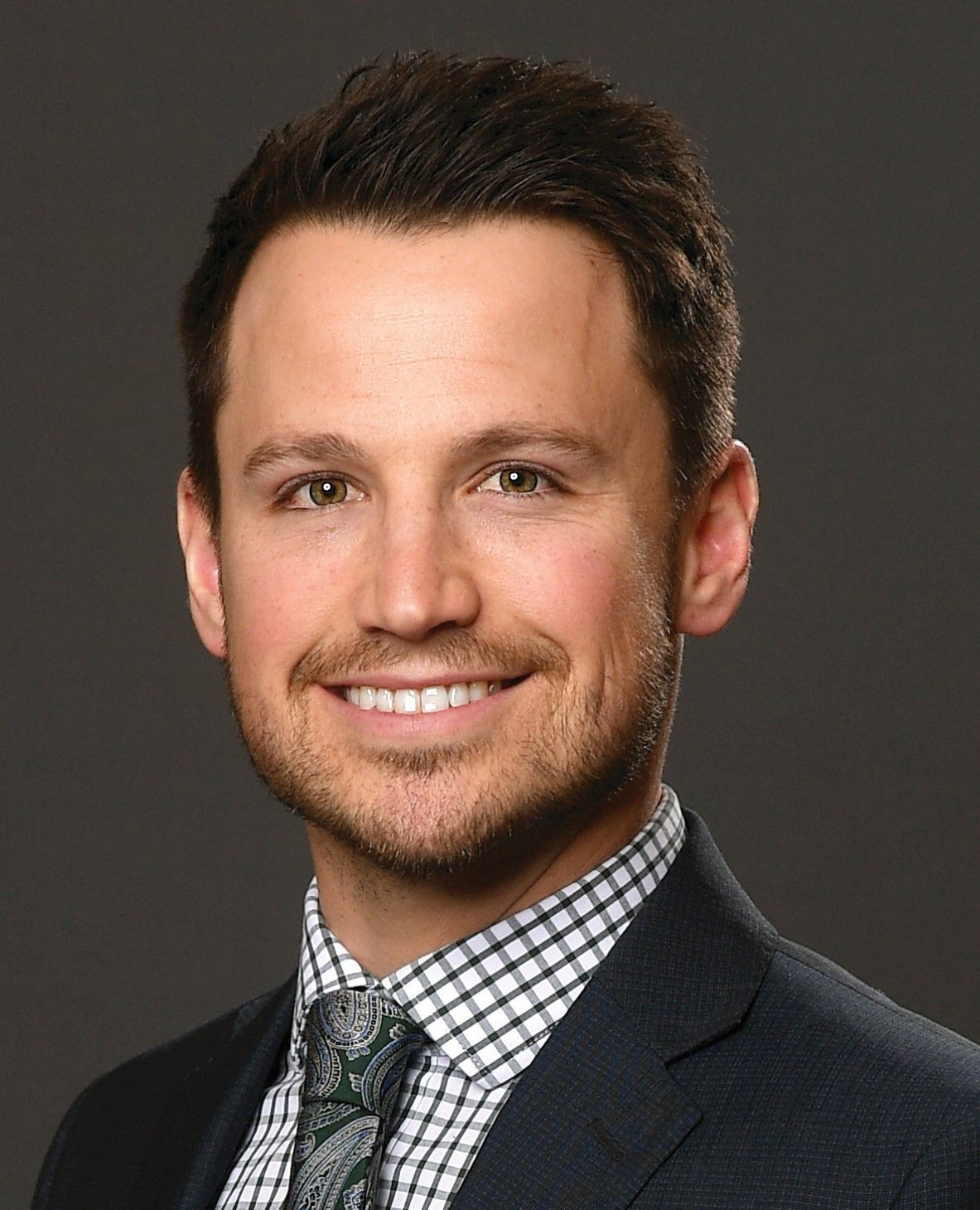 A man in a suit and black turtleneck is looking at the camera.