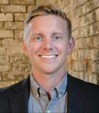 A man in a suit and tie is smiling for the camera.