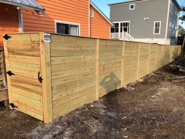 Orange House With Wooden Fence — Wilmington,  NC — J & J Fence