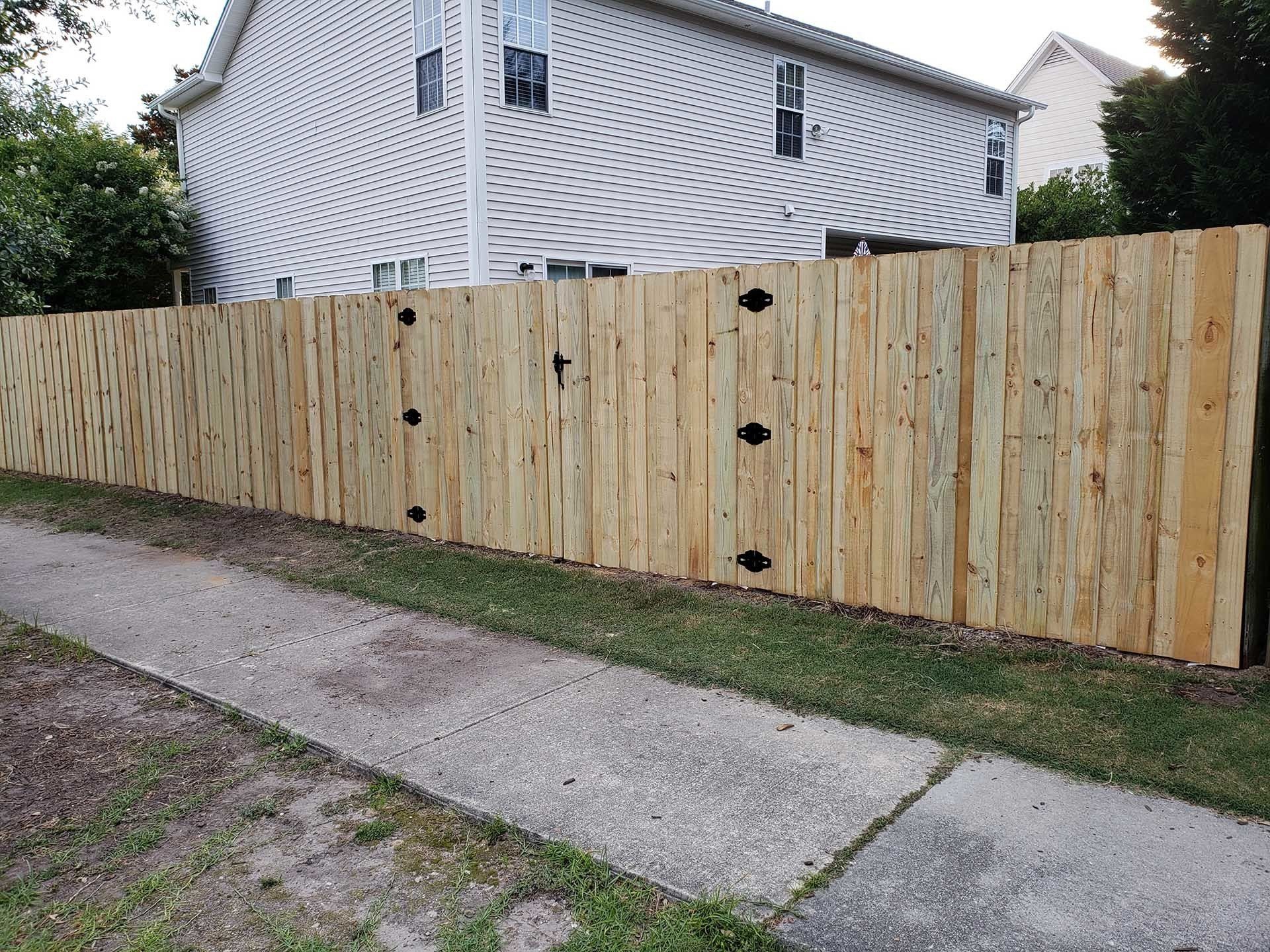 House With White Siding And Wooden Fence Gate — Wilmington,  NC — J & J Fence