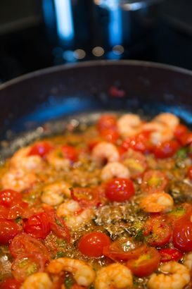 A close up of a pan filled with shrimp and tomatoes.