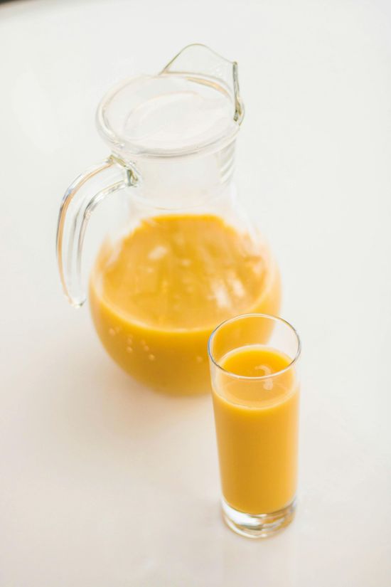 A pitcher of orange juice and a glass of orange juice on a table.