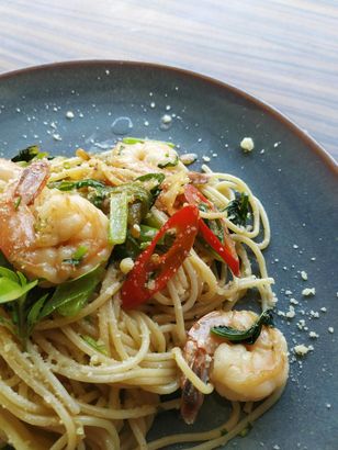 A close up of a plate of spaghetti with shrimp and vegetables