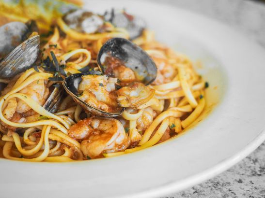 A close up of a plate of spaghetti with clams and shrimp on a table.